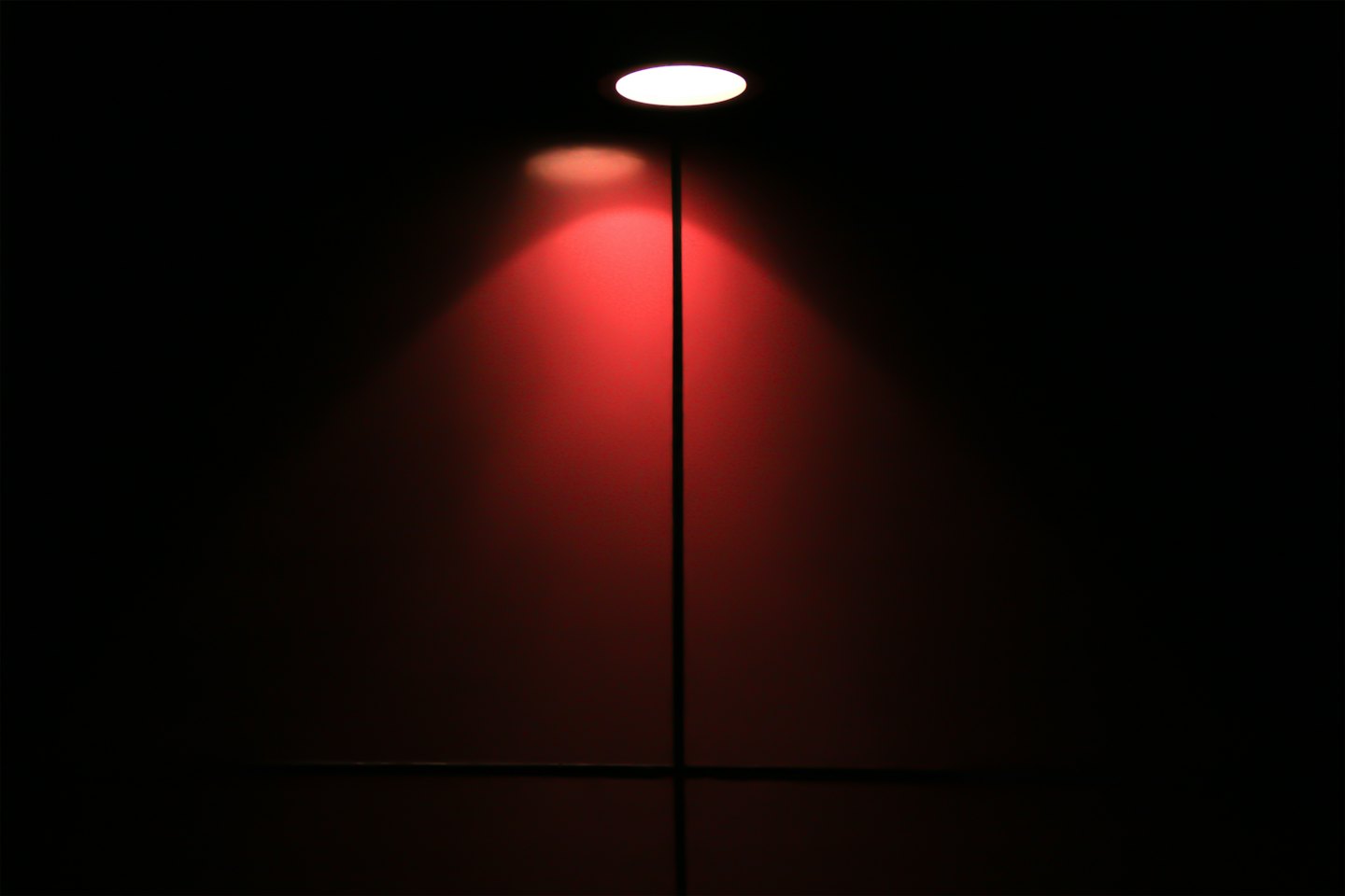 A bright red spotlight shines down on a dark surface.