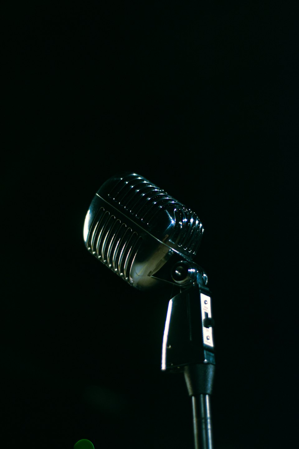 Vintage chrome microphone on a stand on a dark stage.