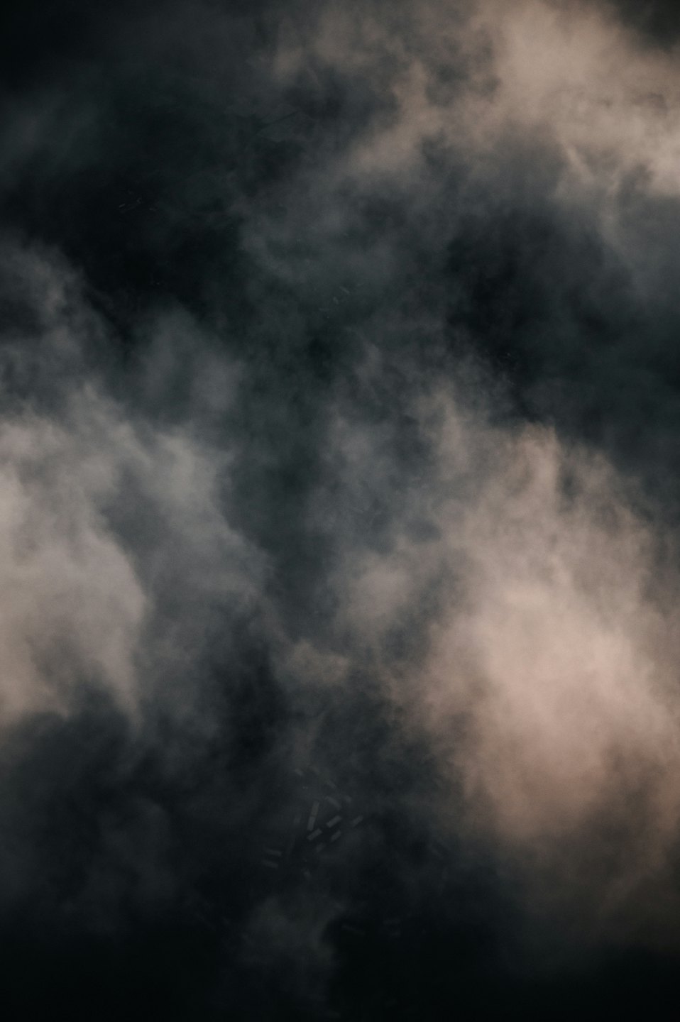Swirling dark grey and black smoke with warm beige highlights.