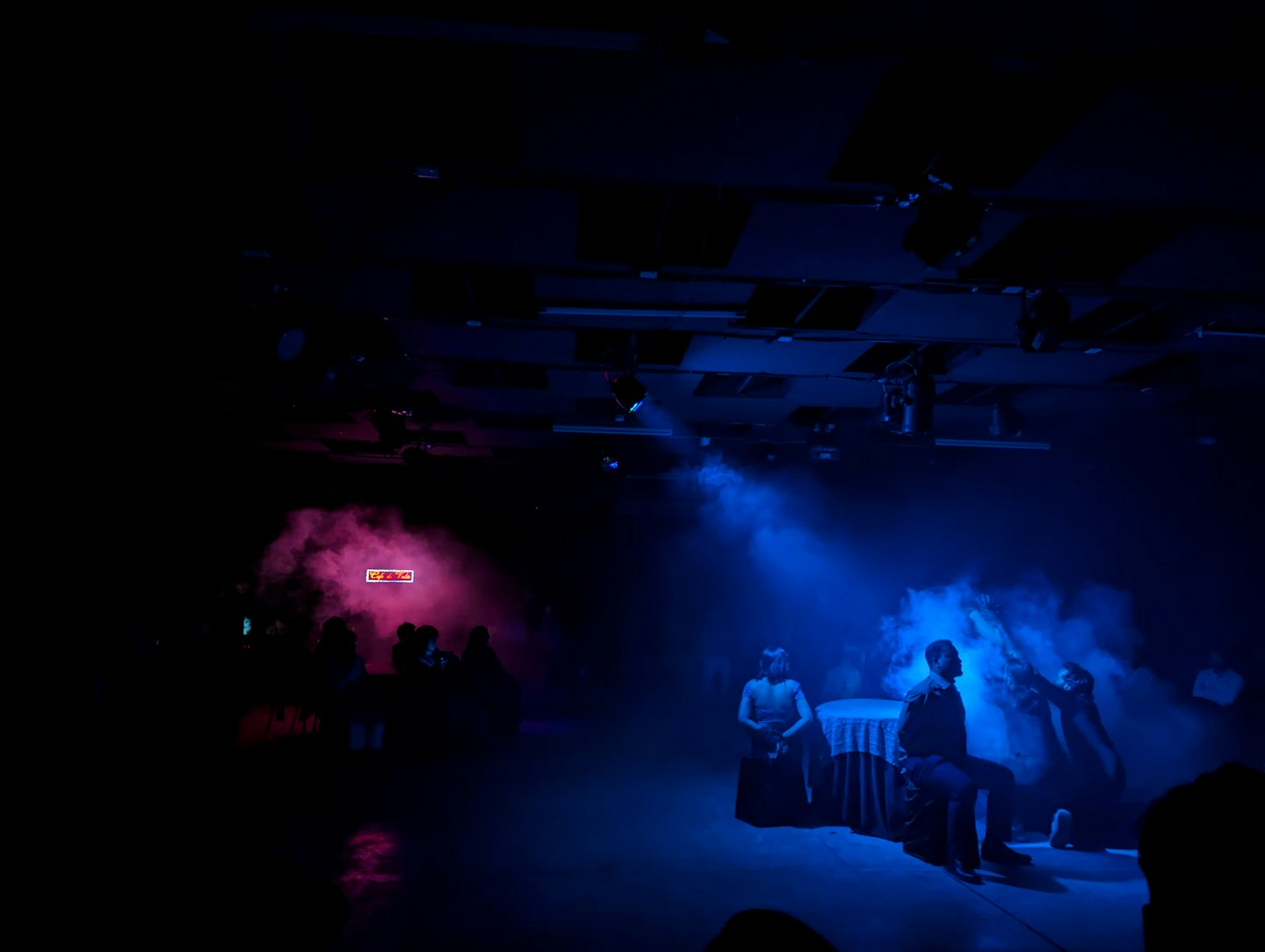 Actors perform on stage with red and blue lights.